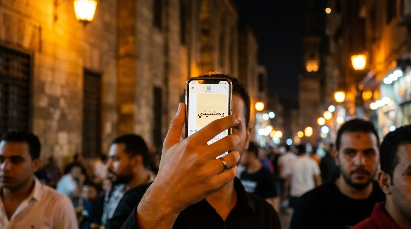 صورة مقربة لهاتف محمول يعرض رسالة نصية بكلمة وحشتني مع خلفية ليلية في القاهرة