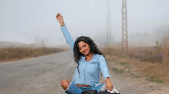 Woman sitting on the road, tossing a jacket into the air.