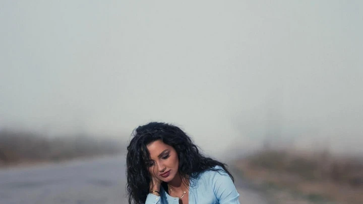 Woman sitting on the road, rummaging through her suitcase.